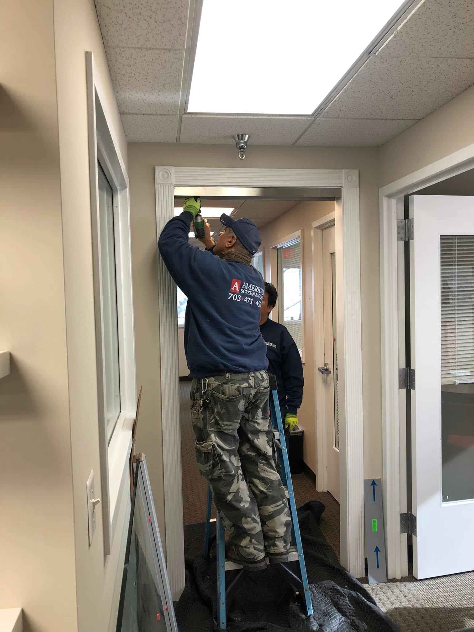 American Screen & Glass technicians in company uniforms installing an office door