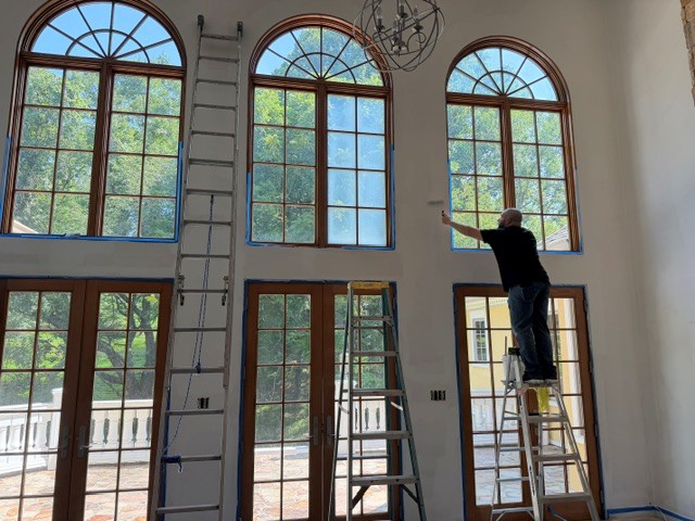 American Screen & Glass installer working on a tall arched window wall inside a home