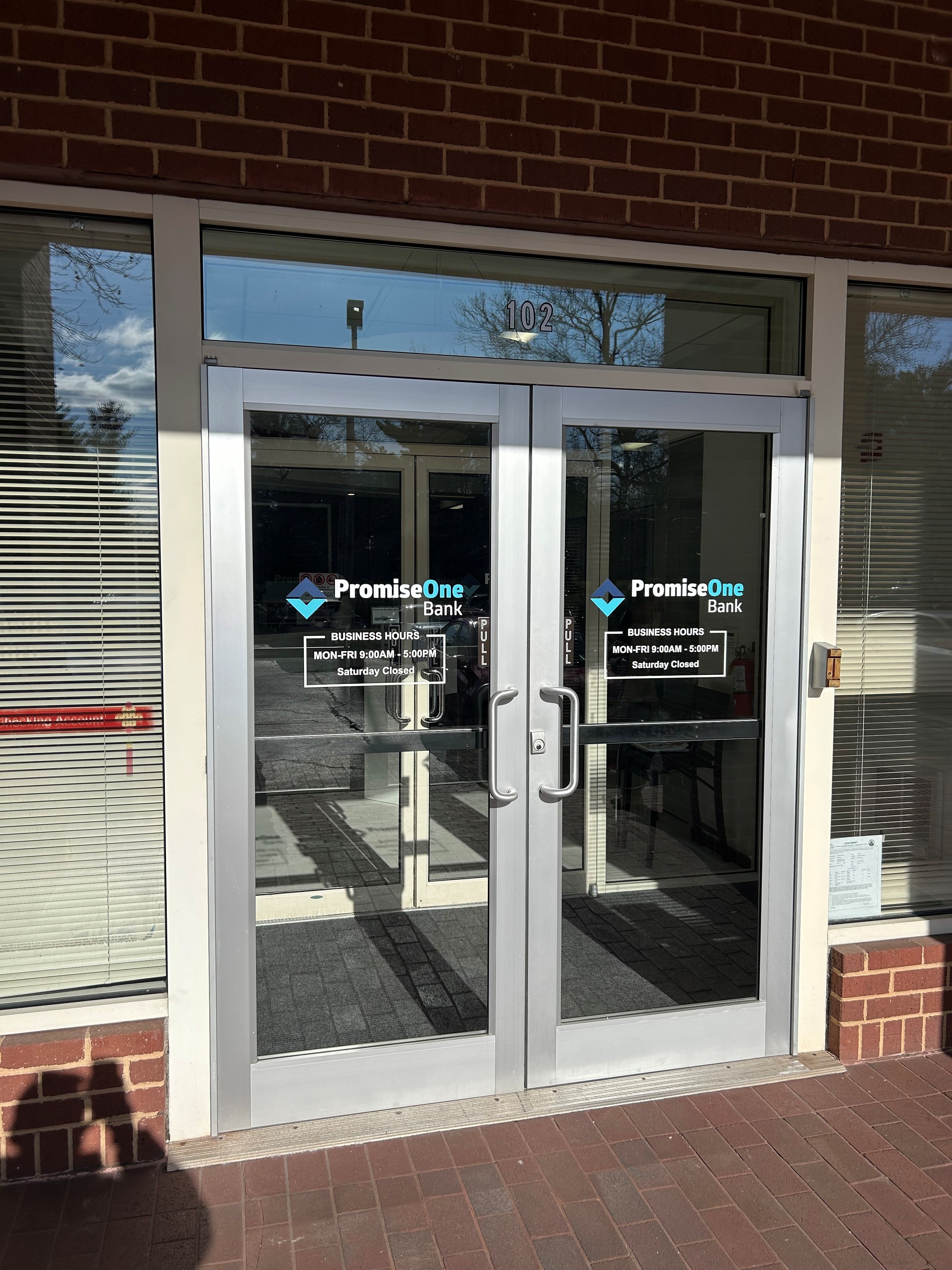 Aluminum-framed double glass doors at a brick storefront.