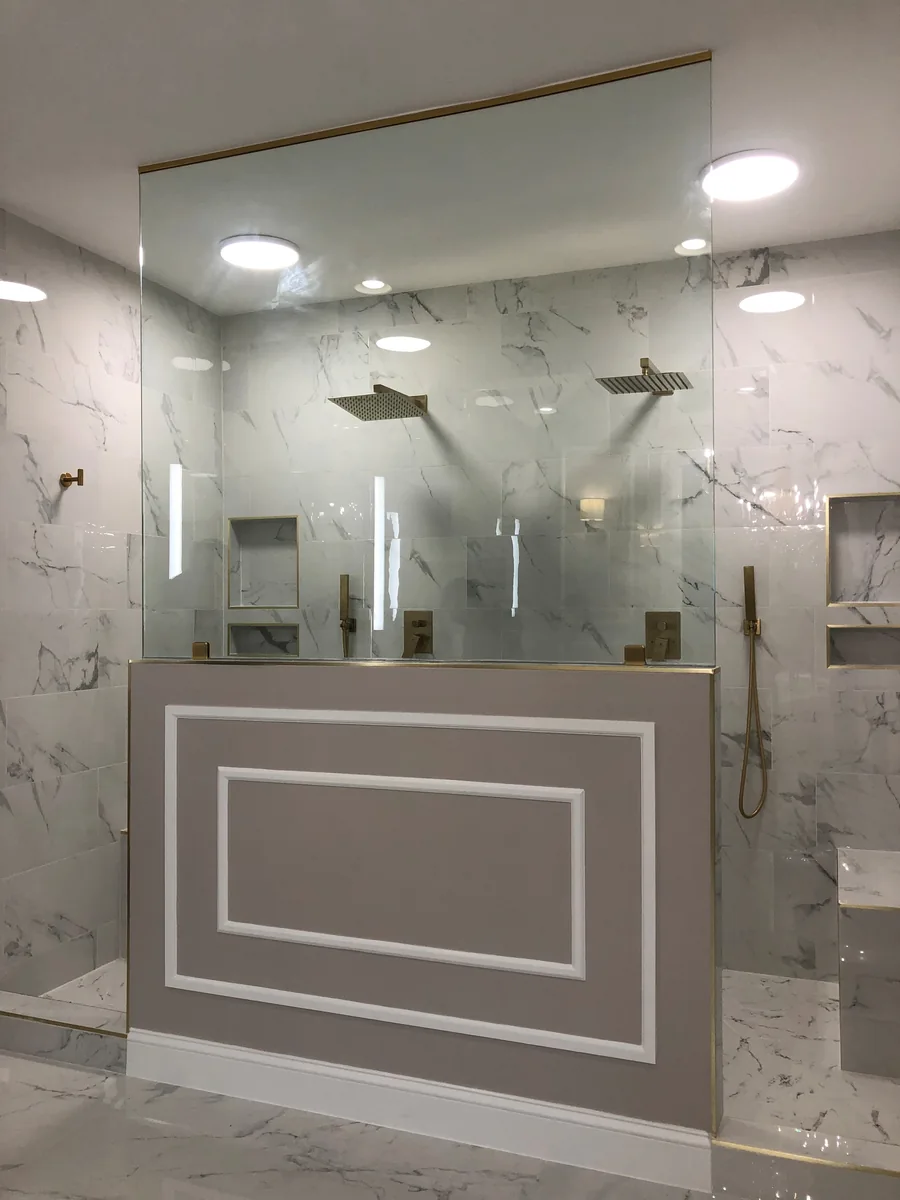 Wide vanity mirror beneath bathroom lights and above the sink