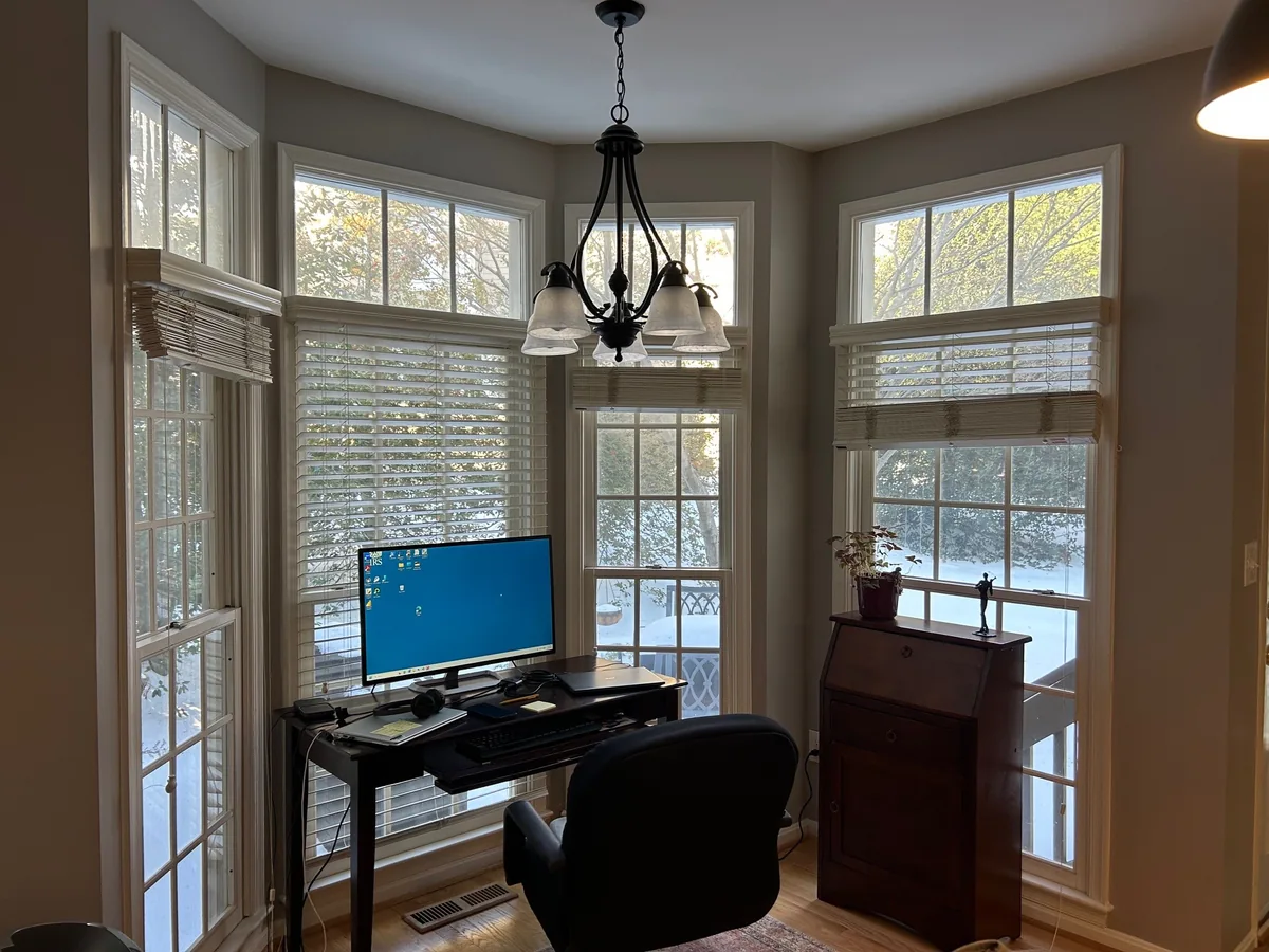 Tall white-framed windows with rectangular transoms around a sunlit room.