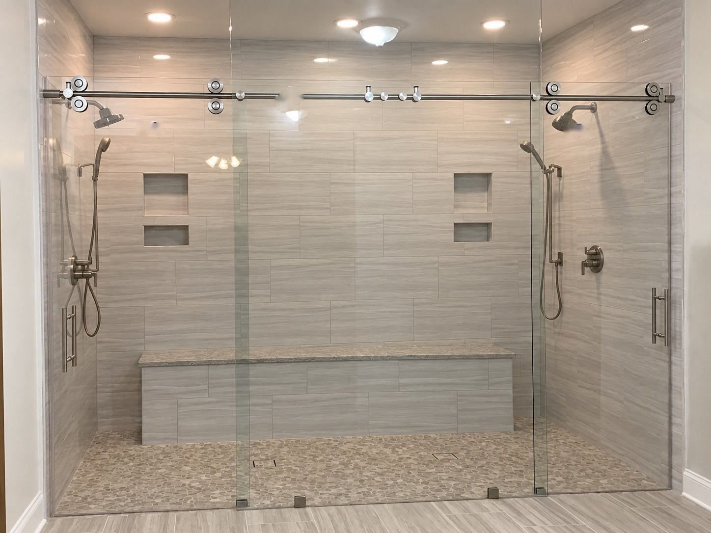 Custom sliding glass shower enclosure with a tiled bench and silver hardware, measured and installed by American Screen & Glass