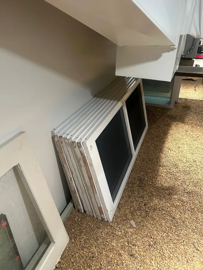 White-framed window screens stacked in a work area.