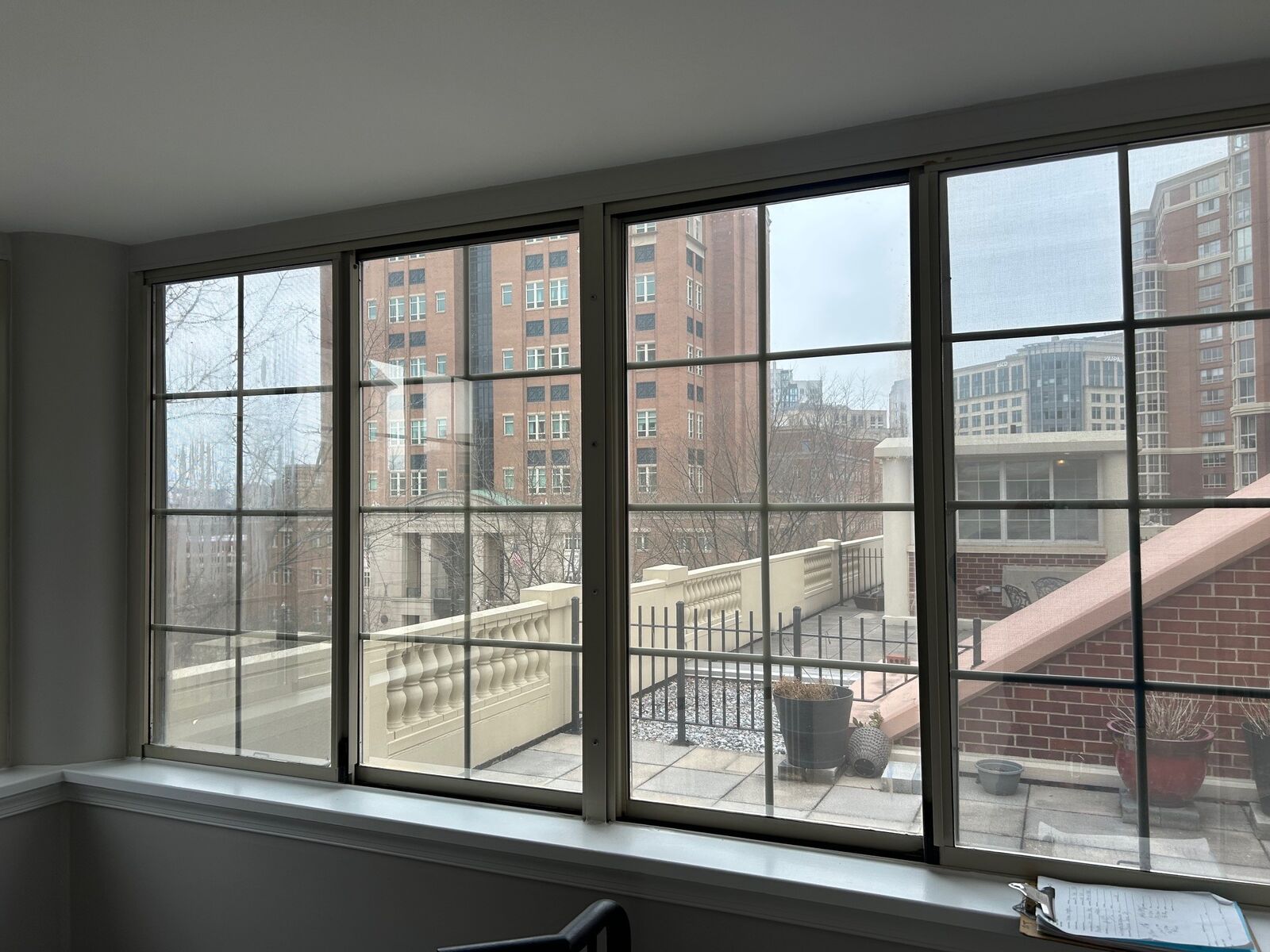 A row of dark-framed windows lining an enclosed condo balcony