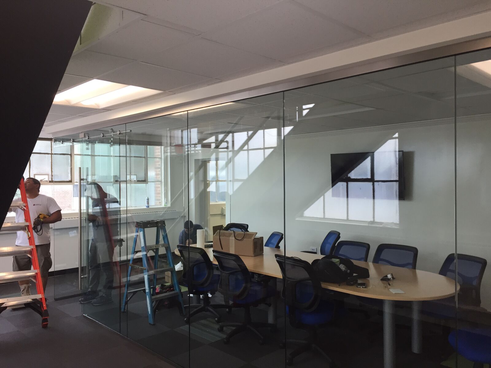 A glass wall bordering a conference room during installation