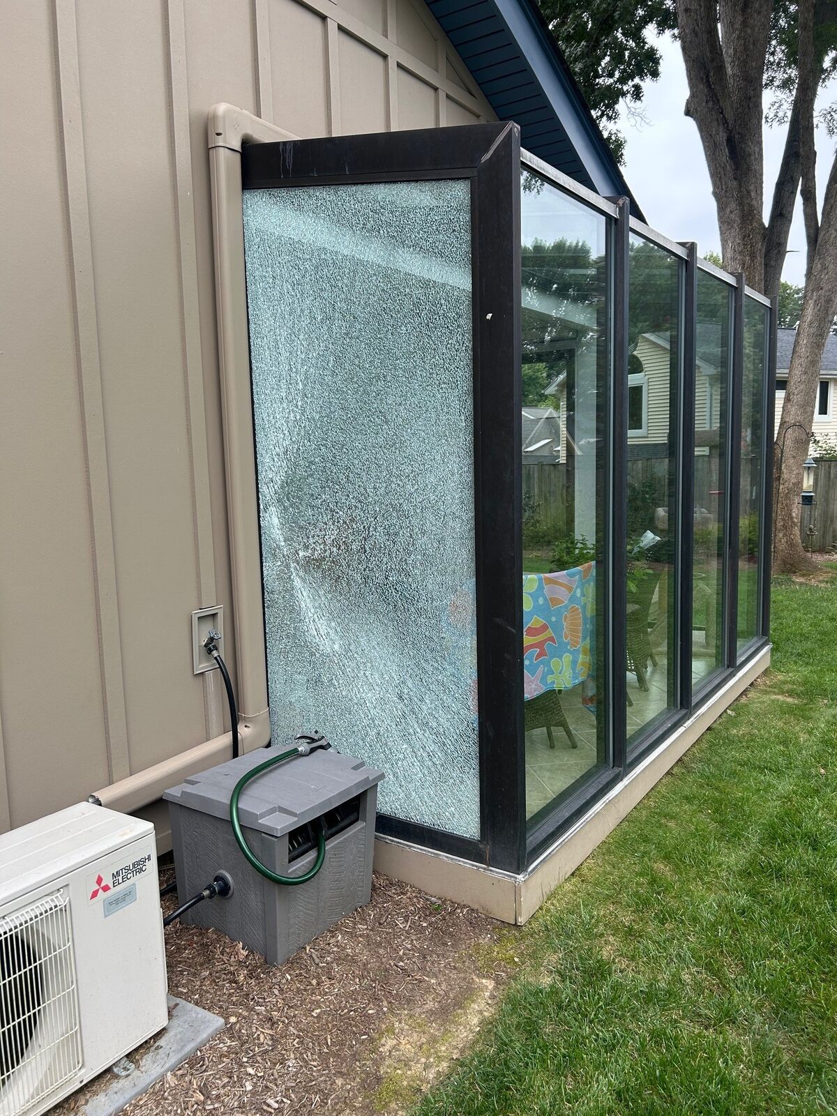 A glass sunroom with one visibly shattered panel