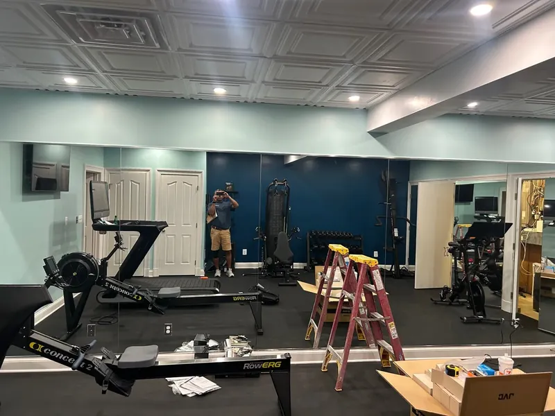 Large wall mirrors reflect equipment in a home gym.