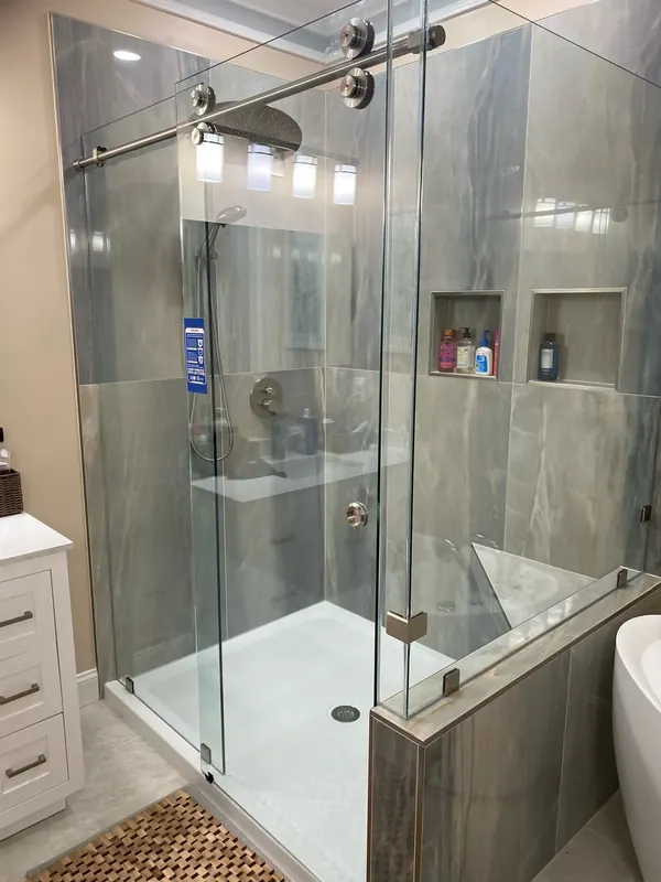 Sliding glass shower enclosure with an exposed roller track.