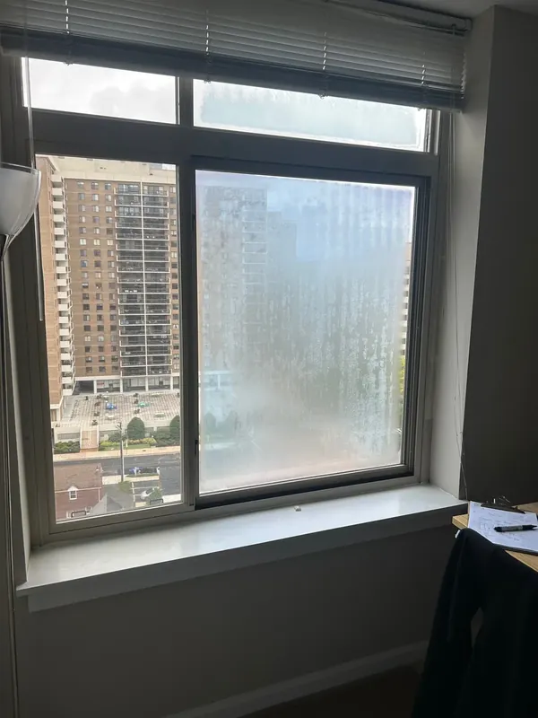 An apartment window has a visibly cloudy pane.