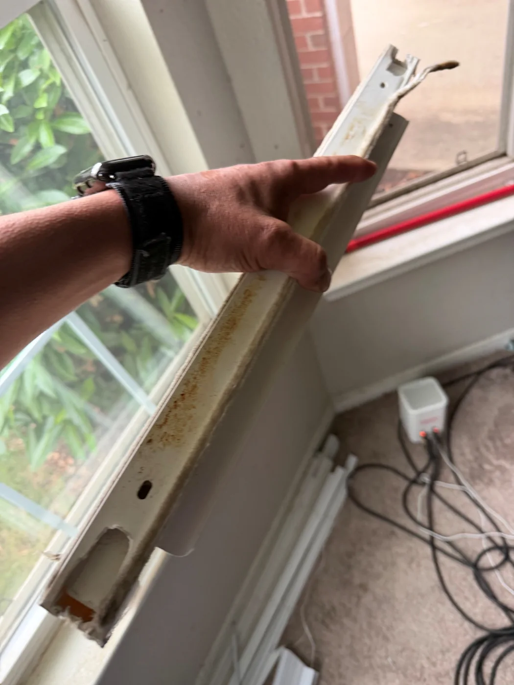 A removed window component is held beside an open sash.