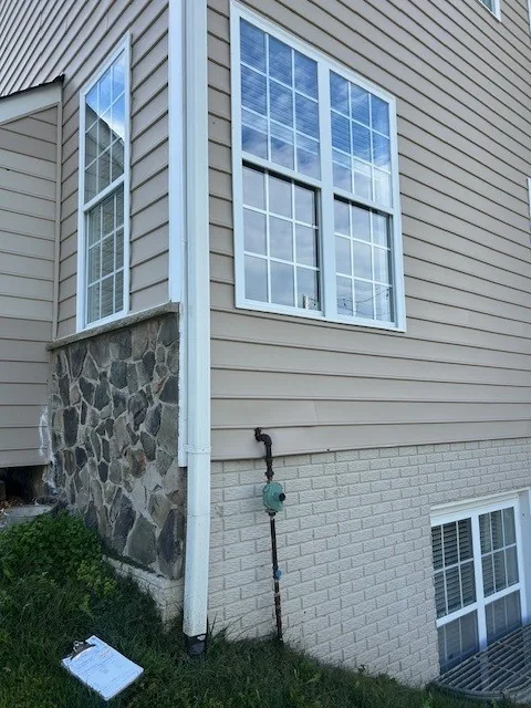 White grid windows are shown on a house corner above stonework.