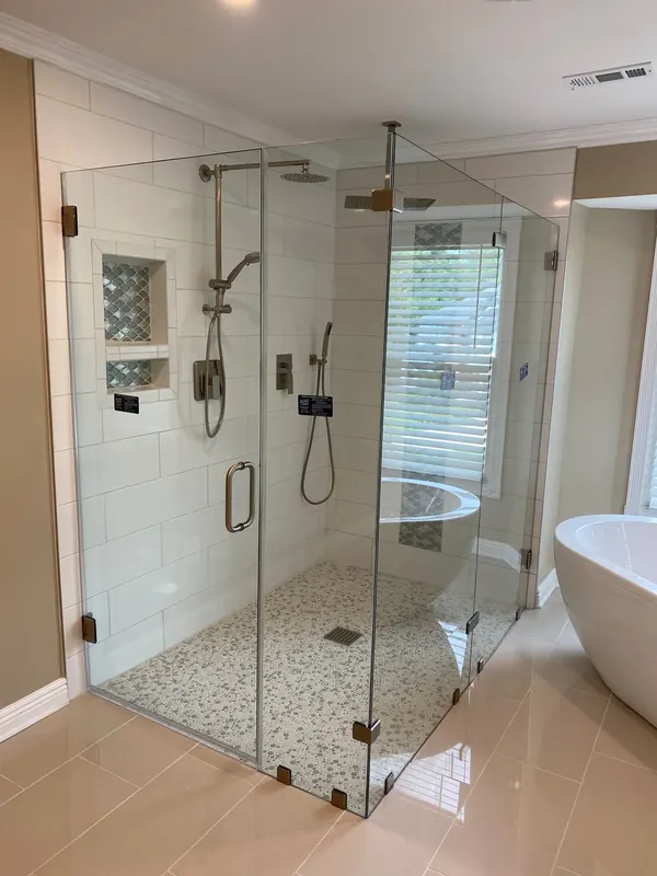 Large glass shower beside a freestanding bathtub.