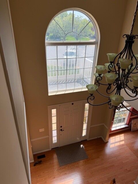 A large arched window above a home's front entry, seen from the two-story foyer
