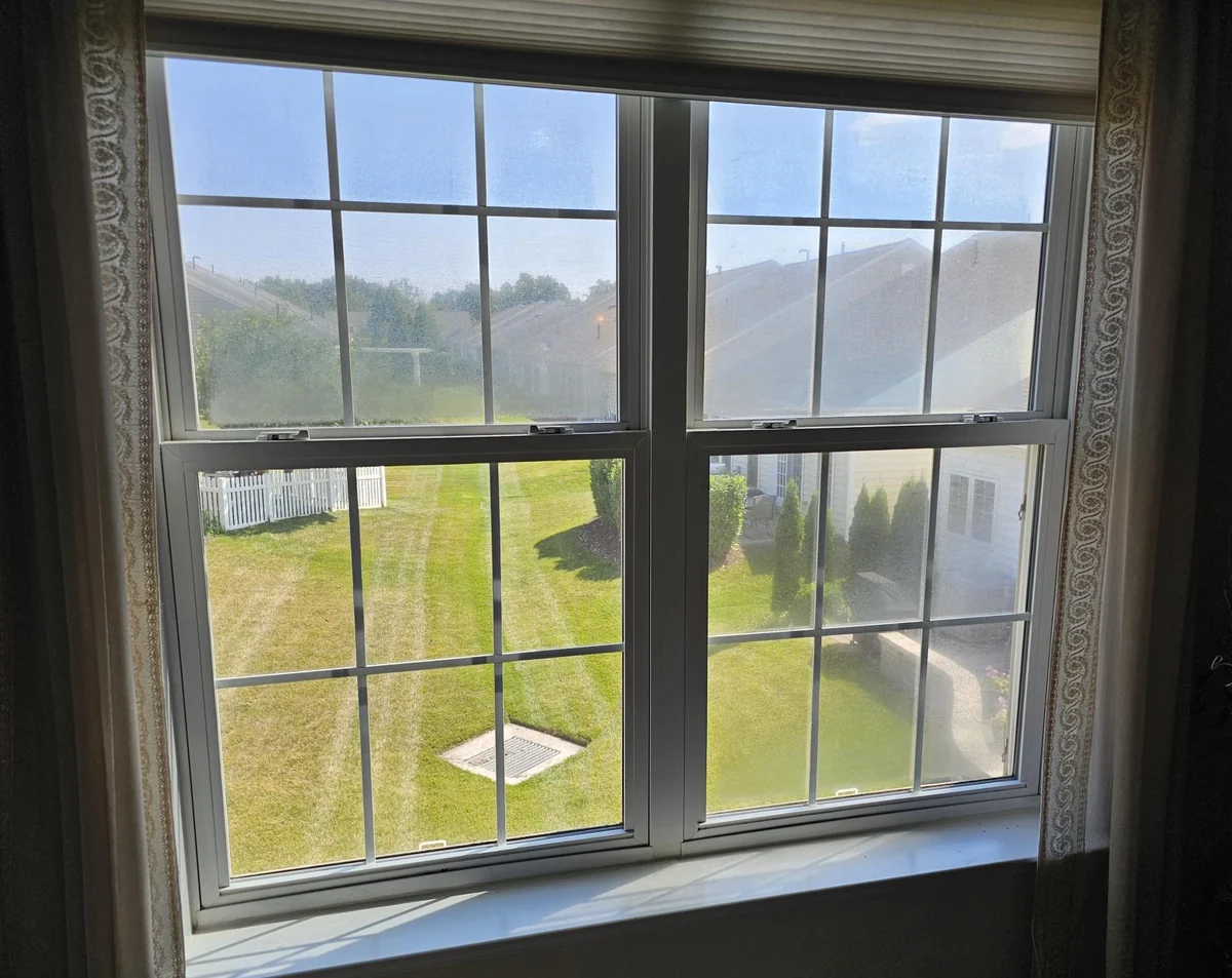 Two white double-hung windows with visible haze in several glass panes