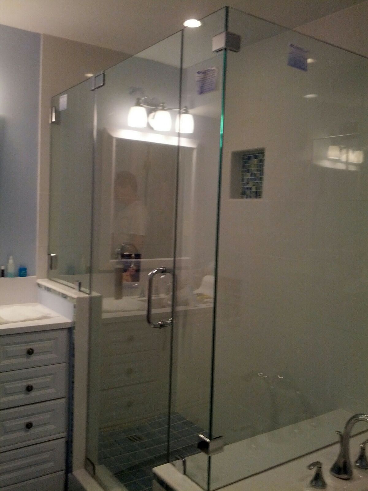 A frameless glass shower enclosure beside a bathroom vanity and bathtub