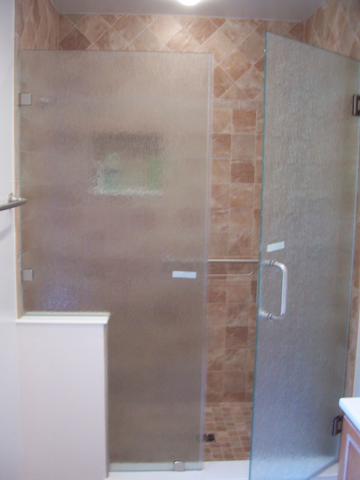 Privacy-textured glass panels and a door enclosing a tiled shower