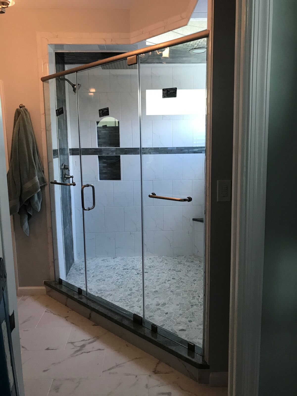 A wide clear glass shower enclosure with an overhead header bar