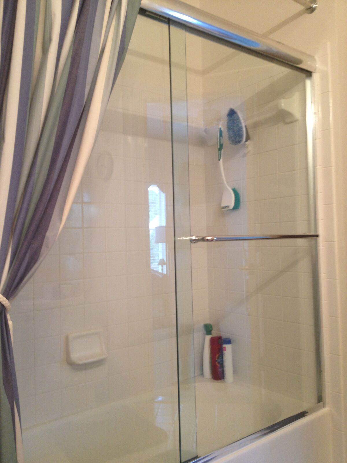 Older-style framed sliding bathtub doors with a chrome frame