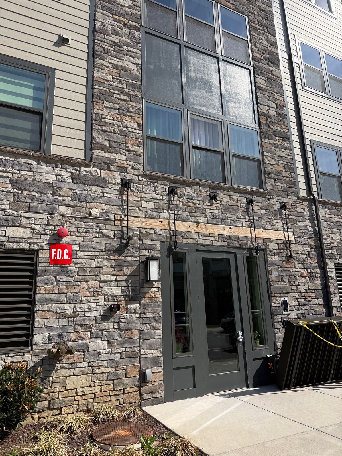 A glass entry door at the base of a stone and brick apartment building