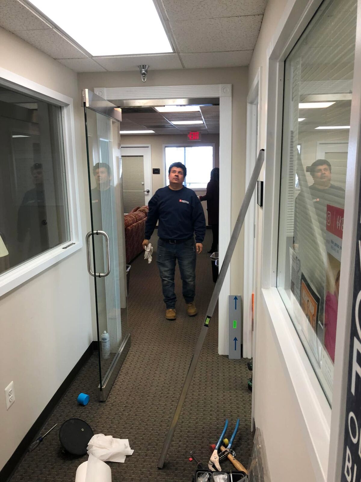 An AS&G technician carrying a glass panel down an office corridor during an interior glass install