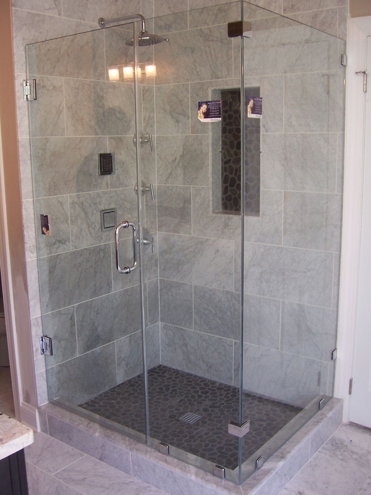 A clear glass corner shower enclosure with chrome-tone hinges