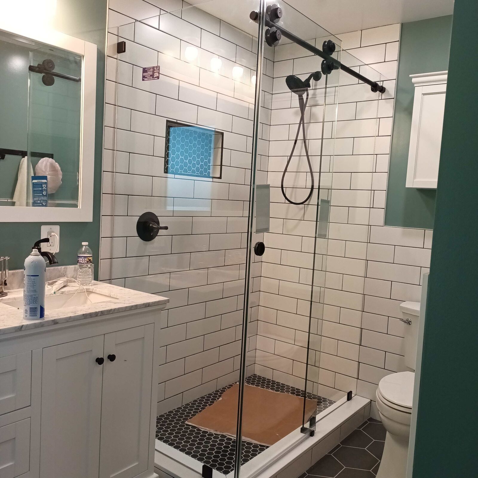 A glass shower with black hardware against white subway tile