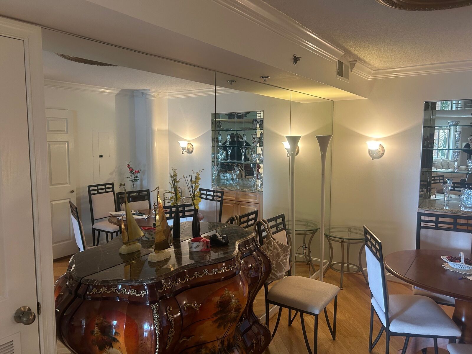 A wall of mirror panels reflecting a furnished dining room