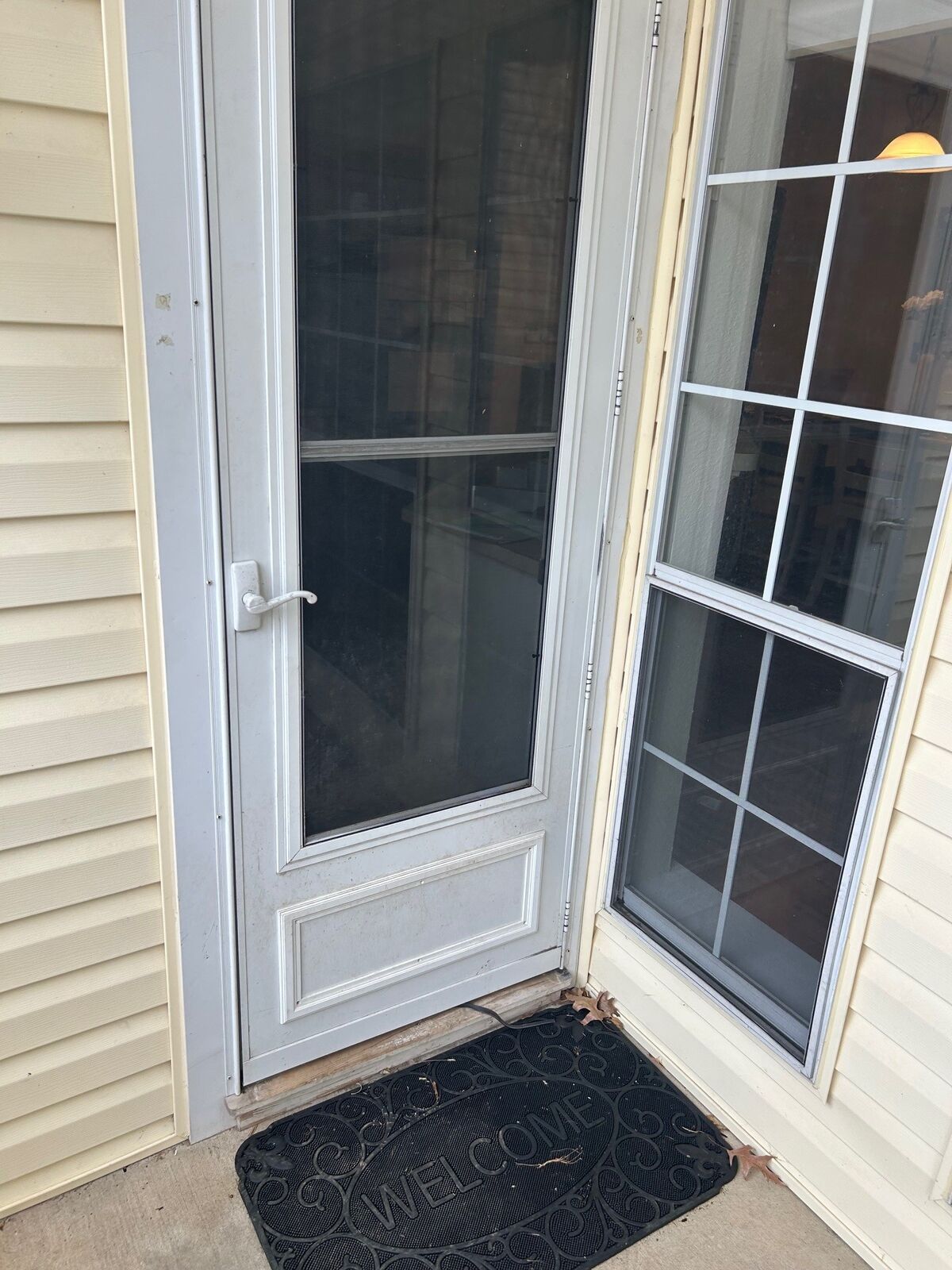 A white screen door standing open at a patio entry beside a door with grids