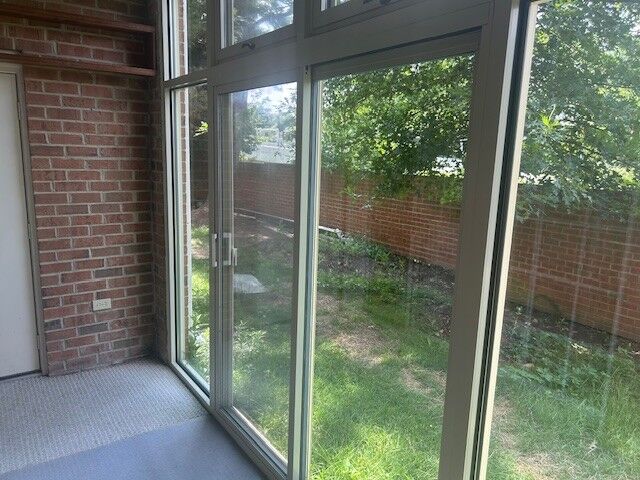 An enclosed porch with tall window panels looking onto a yard