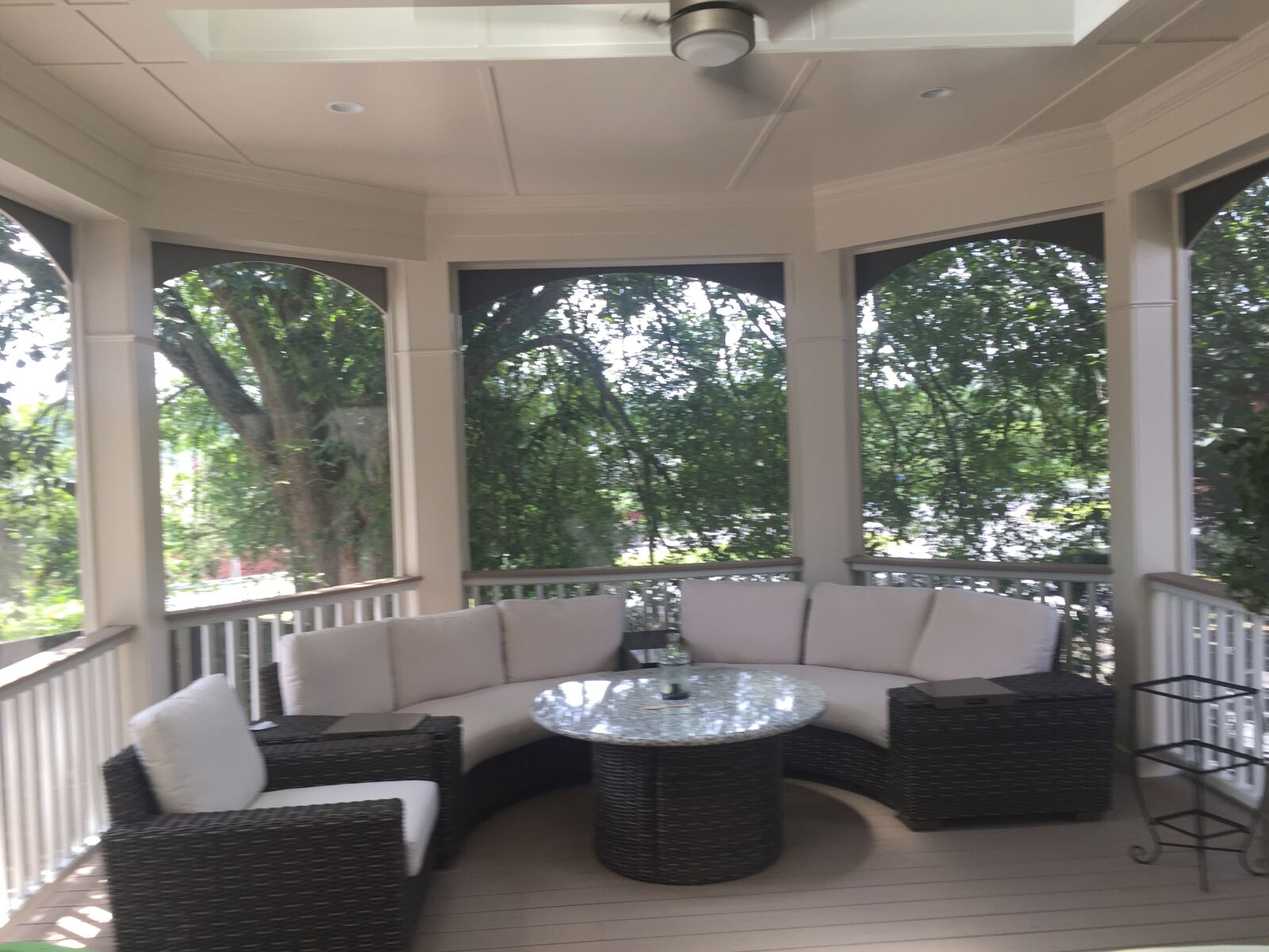 A screened porch with arched openings and a curved sectional sofa
