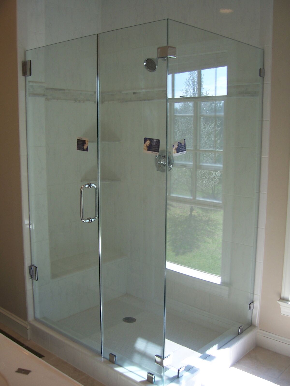 A frameless glass shower enclosure built around a tall window