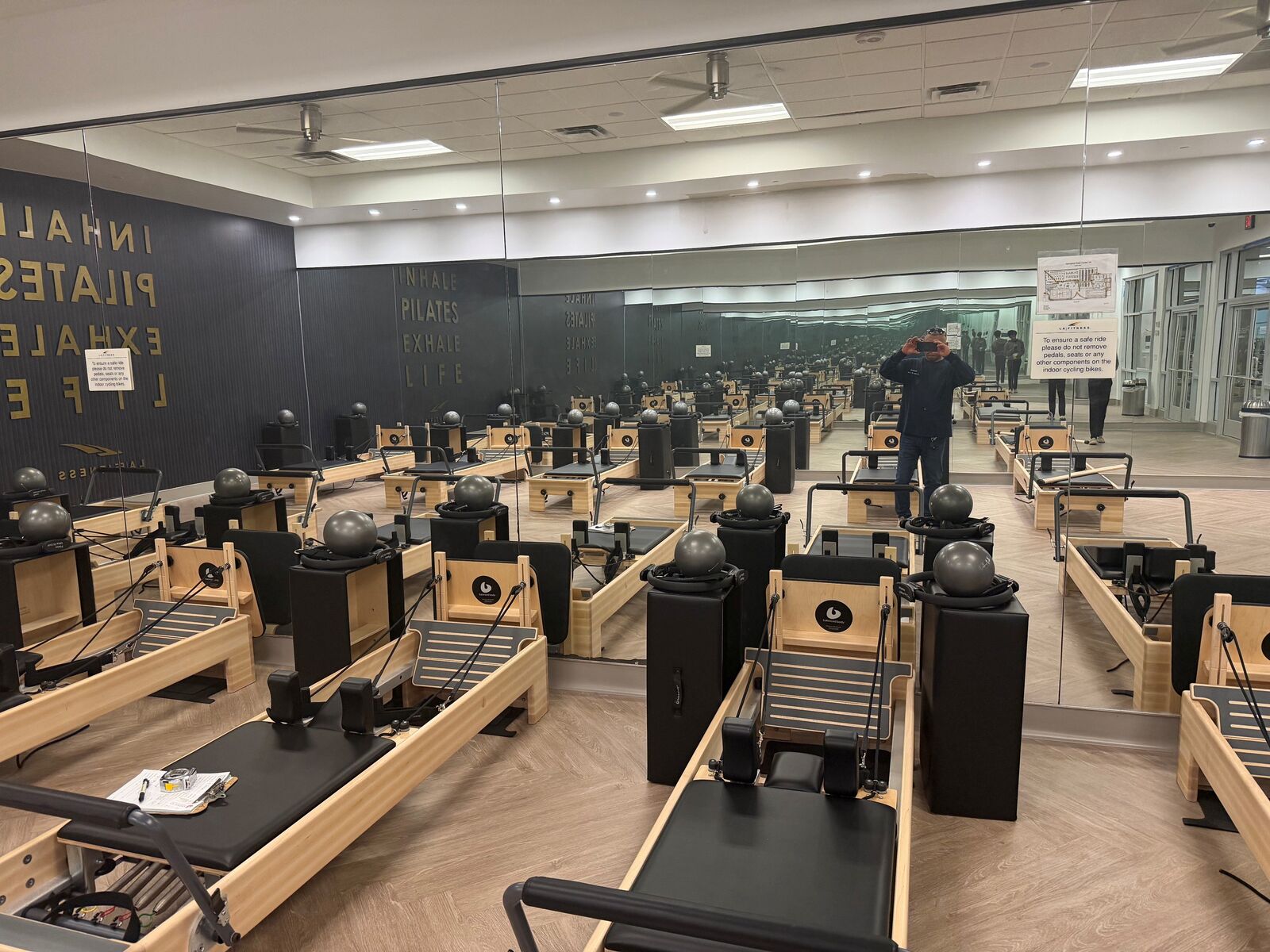 A full-width mirror wall reflecting Pilates equipment in a studio