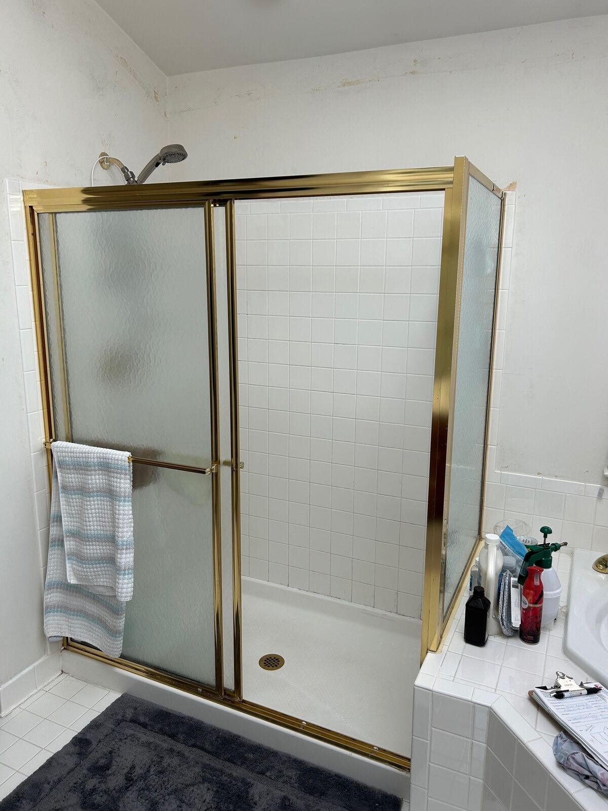 An older gold-tone framed shower enclosure with frosted glass