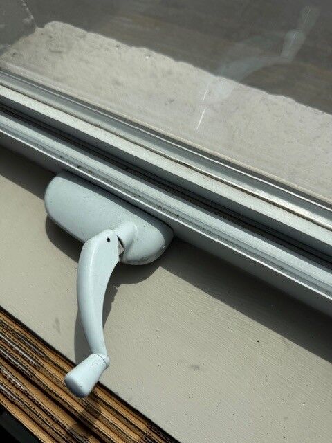 Close-up of a white casement window crank
