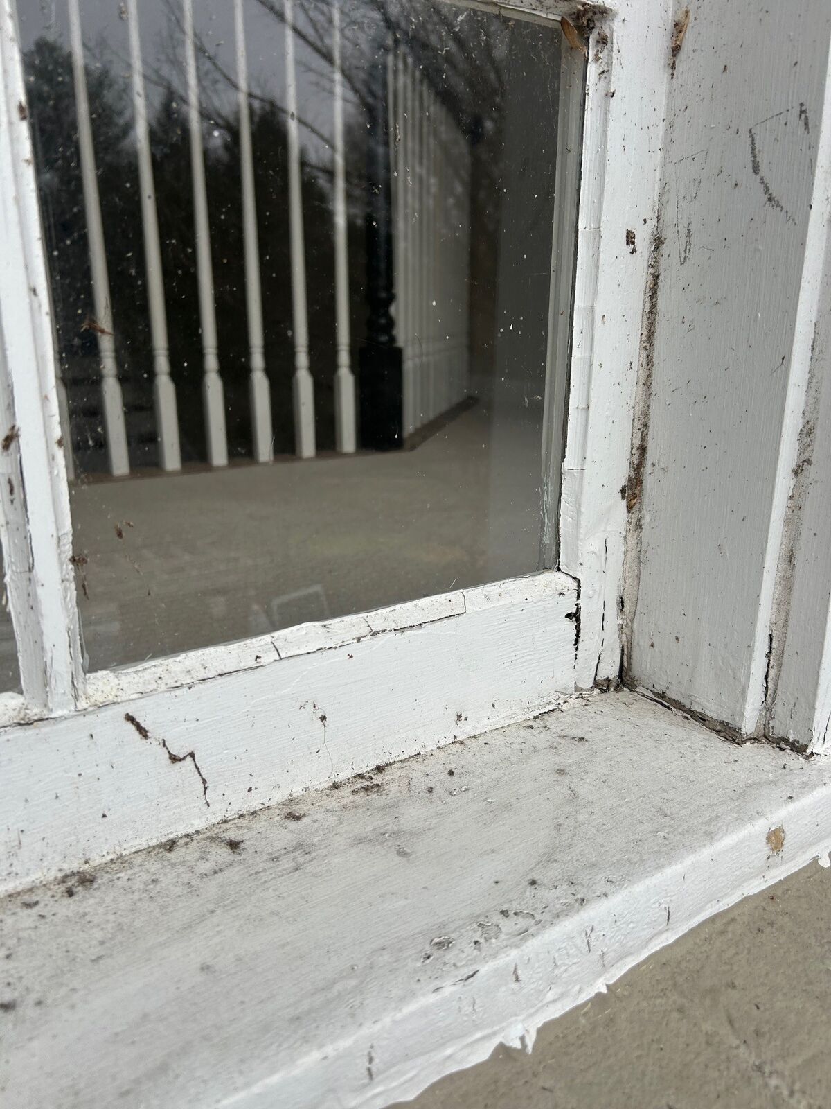 A painted wood window frame corner with worn paint and debris